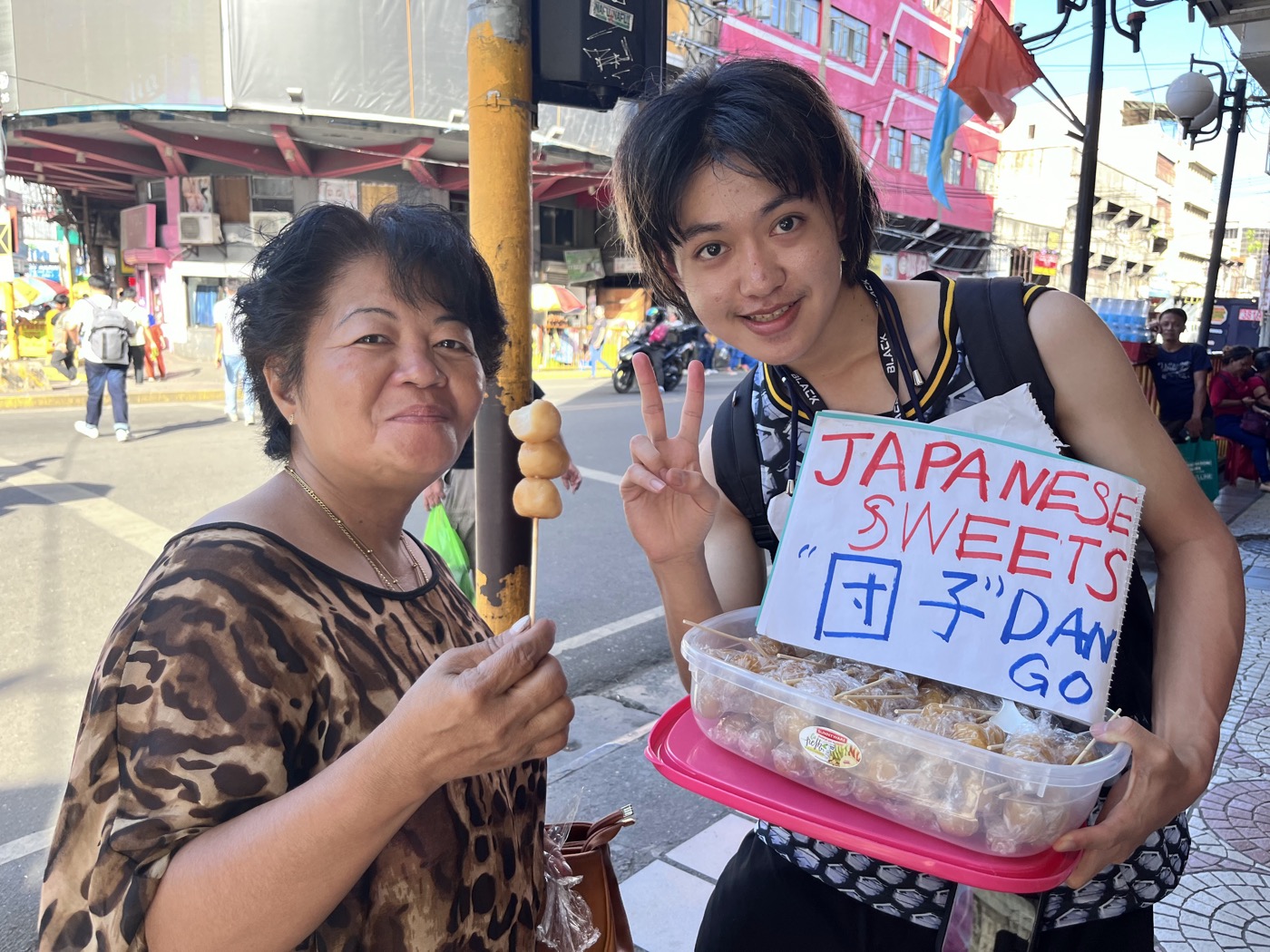 手作りの看板を掲げ、日本の団子を現地の女性に売る参加者